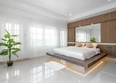 Modern bedroom with a large bed, plants, and ample natural light