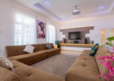 Modern living room with brown sofas, flat-screen TV, and decorative elements