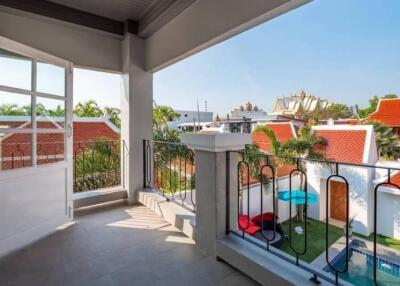 Spacious balcony with a view of red-tiled roof houses and a well-maintained garden area