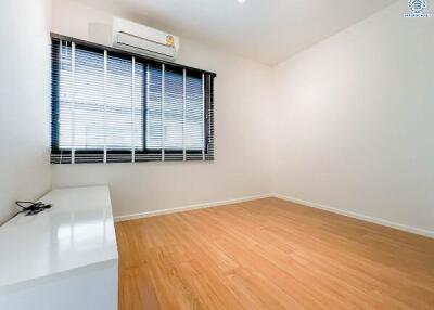 Spacious bedroom with wooden flooring and large window