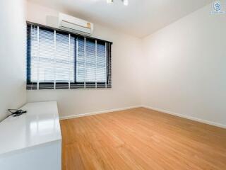 Spacious bedroom with wooden flooring and large window