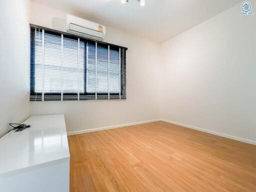 Spacious bedroom with wooden flooring and large window