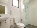 Modern bathroom with toilet, sink, and glass shower