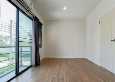 Spacious bedroom with wooden flooring and large window