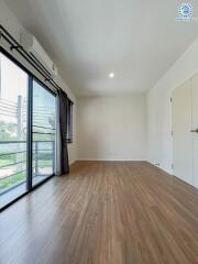 Spacious bedroom with wooden flooring and large window