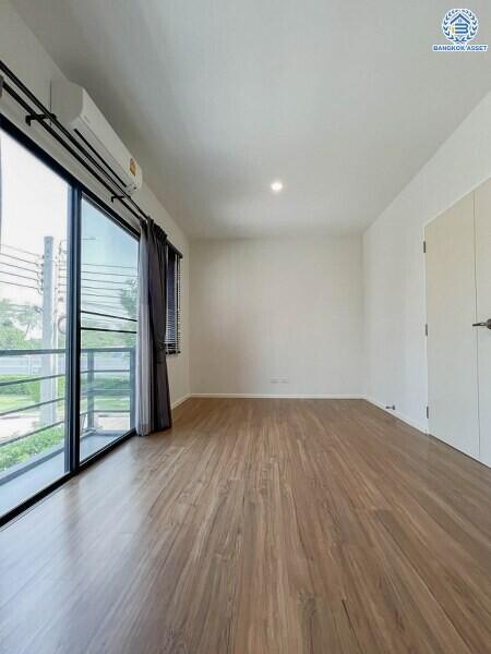 Spacious bedroom with wooden flooring and large window