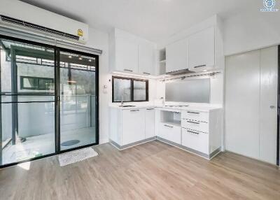 Modern kitchen with white cabinets and sliding door to balcony