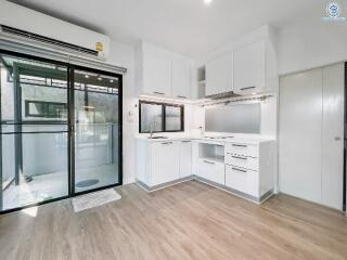 Modern kitchen with white cabinets and sliding door to balcony