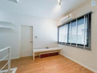 Modern bedroom with wooden floor, window blinds, air conditioning, and a bench