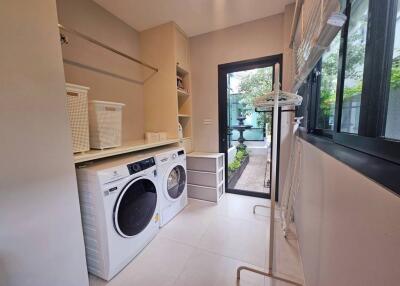 Laundry room with washer and dryer, storage baskets, and a window.