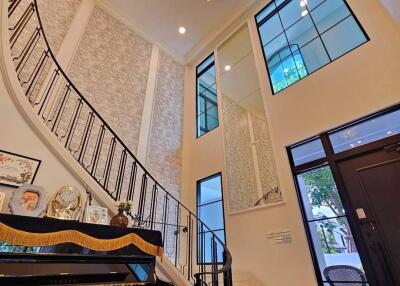 Spacious living room with high ceiling and grand staircase