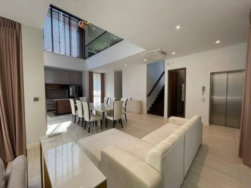 Modern living room with high ceiling, dining area, and staircase