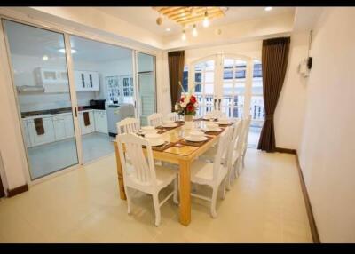 Elegant dining area with table set for eight, adjacent to kitchen