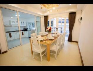 Elegant dining area with table set for eight, adjacent to kitchen