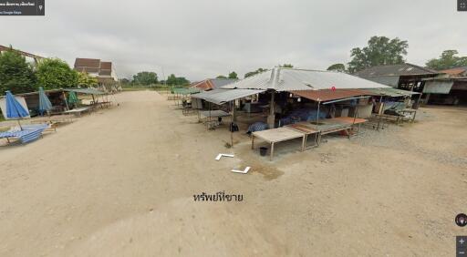 Outdoor market with multiple stalls covered by metal roofs