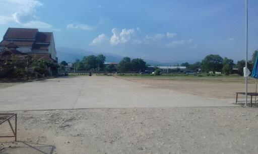 Open outdoor area with a partially visible building and mountains in the background