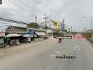 Street view with shops, vehicles, and electrical wires