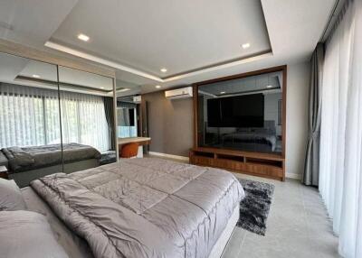 Spacious modern bedroom with large mirrored closet and wall-mounted TV