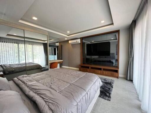 Spacious modern bedroom with large mirrored closet and wall-mounted TV