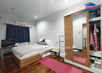 Modern bedroom with wooden furniture and a wardrobe, featuring a large bed and a television.