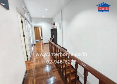 Well-lit hallway with wooden floors and railing