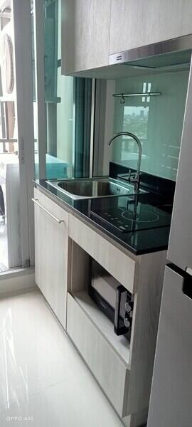 Modern compact kitchen with stainless steel sink, overhead cabinets, and large window