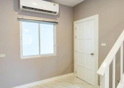 Living area with window, air conditioning unit, and stair rail