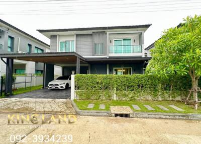 Exterior view of a modern two-story house with a carport and a garden