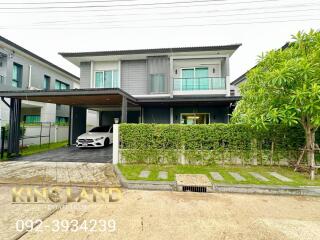 Exterior view of a modern two-story house with a carport and a garden