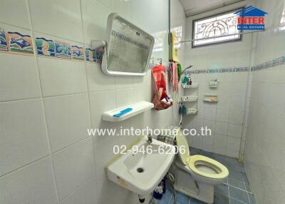 A bathroom with white tiled walls and a small sink