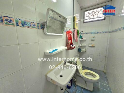 A bathroom with white tiled walls and a small sink