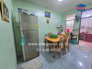 Dining area in a kitchen with a refrigerator, dining table, and microwave