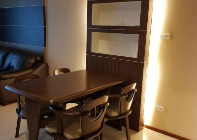 Modern dining area with a dark wooden table and chairs, accented by warm lighting