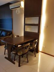 Modern dining area with a dark wooden table and chairs, accented by warm lighting