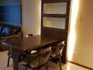 Modern dining area with a dark wooden table and chairs, accented by warm lighting