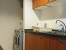 Compact kitchen with wooden cabinets and washing machine