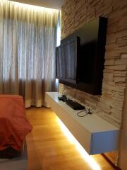 Modern bedroom with a wall-mounted TV and stone accent wall