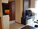 modern living room with TV, cabinets, and a view into the hallway