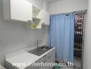 simple kitchen with white cabinets and a blue curtain