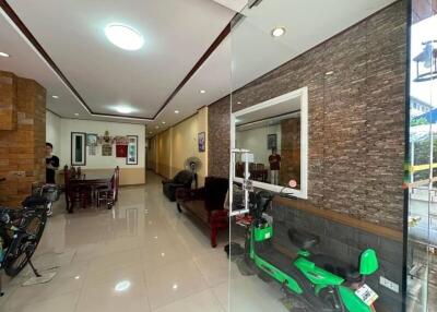 Main living and dining area with a brick wall, glass partition, bikes, and furniture