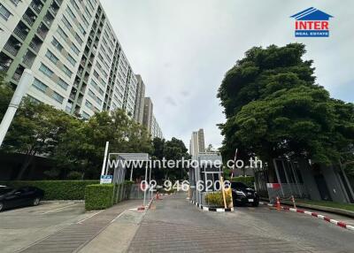 Entrance of a residential building complex with trees and parked cars