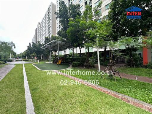 Outdoor garden area with green lawn and trees alongside a tall apartment building