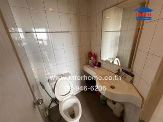 Modern bathroom with white tiles, a toilet, and a sink with a mirror