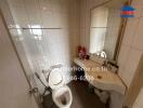 Modern bathroom with white tiles, a toilet, and a sink with a mirror