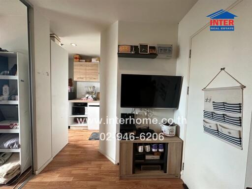 Living area with wall-mounted TV and view into the kitchen