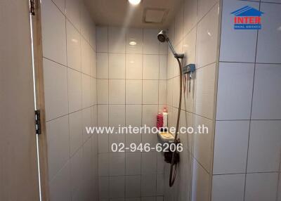 Shower area with white tile walls