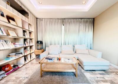 Spacious and bright living room with cozy seating and a bookshelf