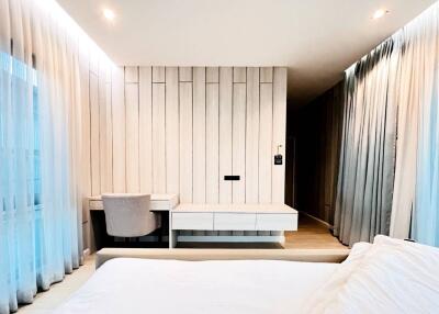 Modern bedroom with light wood paneling, desk, and chair