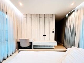 Modern bedroom with light wood paneling, desk, and chair