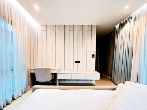 Modern bedroom with light wood paneling, desk, and chair